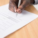 A hand holding a pen over a white loan application form on a table